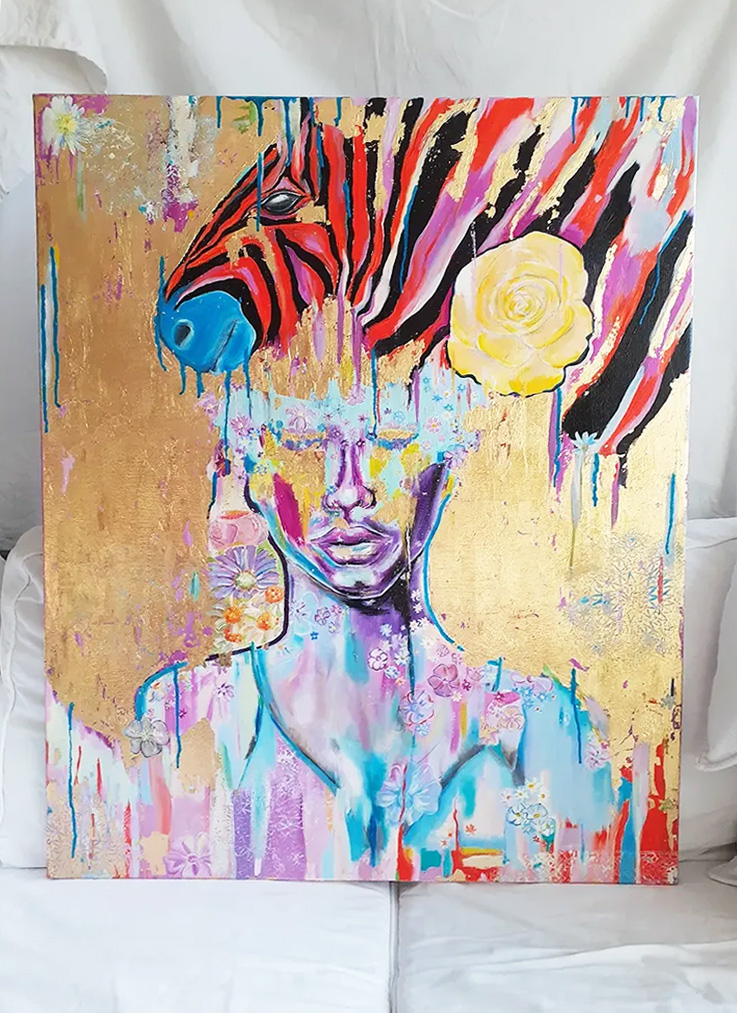 Eine verträumt aussehende Frau hinter bzw. mit Blumen unter einem bunten Zebrakopf. Das Zebra ist künstlerisch gestaltet und hat z. B. ein königsblaues Maul.