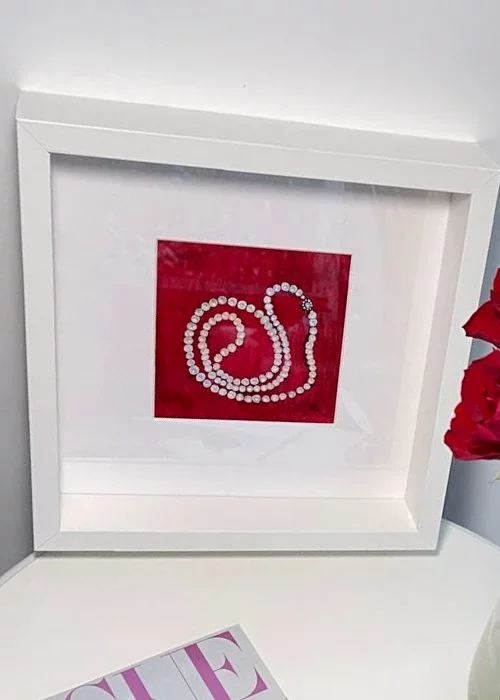 Elegantes Aquarell mit einer Perlenkette auf rotem Hintergrund mit einem weissen, tiefen Rahmen
